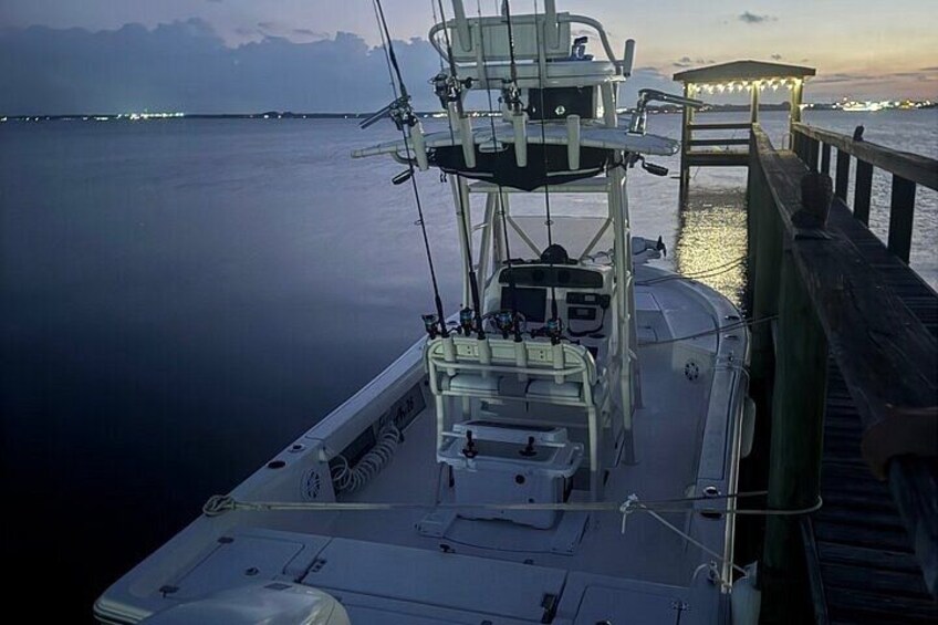 A boat docked at a pier with calm water and a sunset in the background. 3