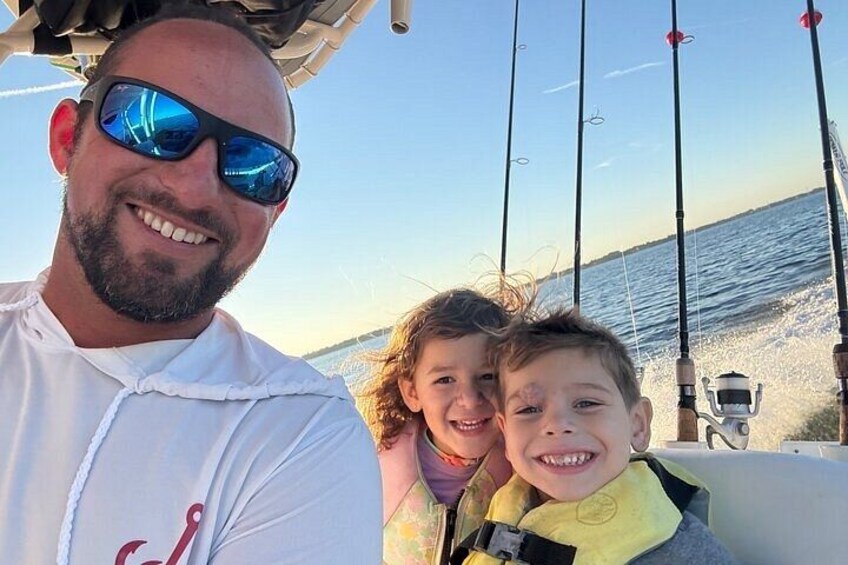 Un bateau équipé de cannes à pêche, une personne portant un gilet de sauvetage et une mer calme en arrière-plan. 2
