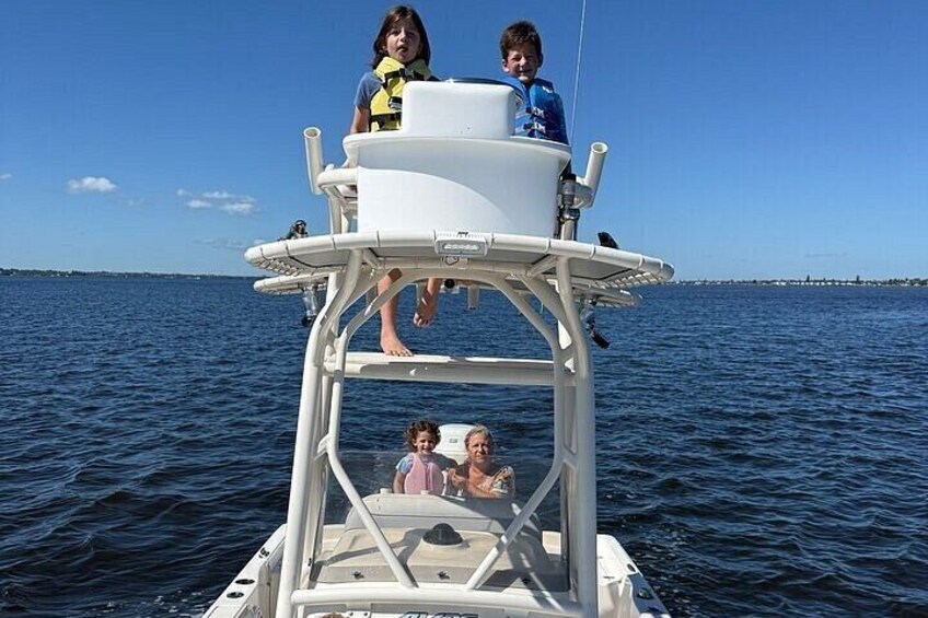 A boat with two people on the top platform and one person on the lower platform. 4