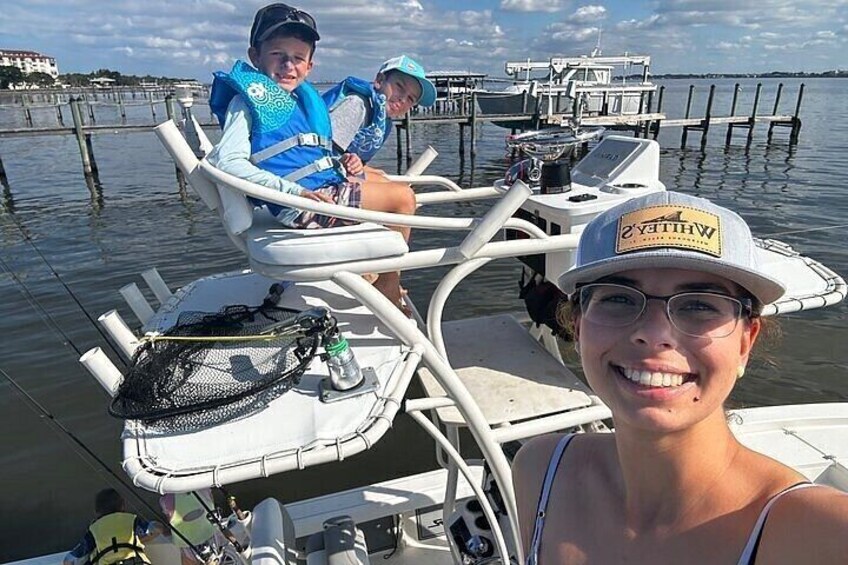 A boat docked at a pier with two people wearing life jackets. 2