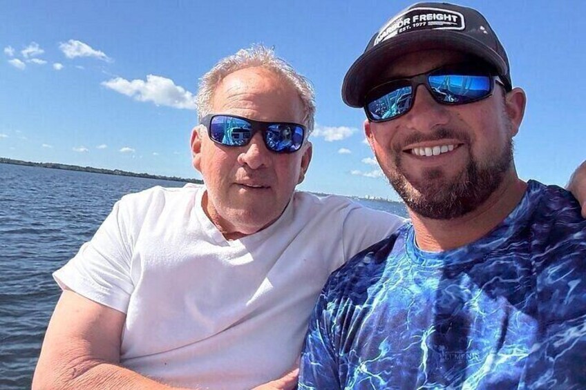 Two people on a boat with a body of water and a clear sky in the background. 5