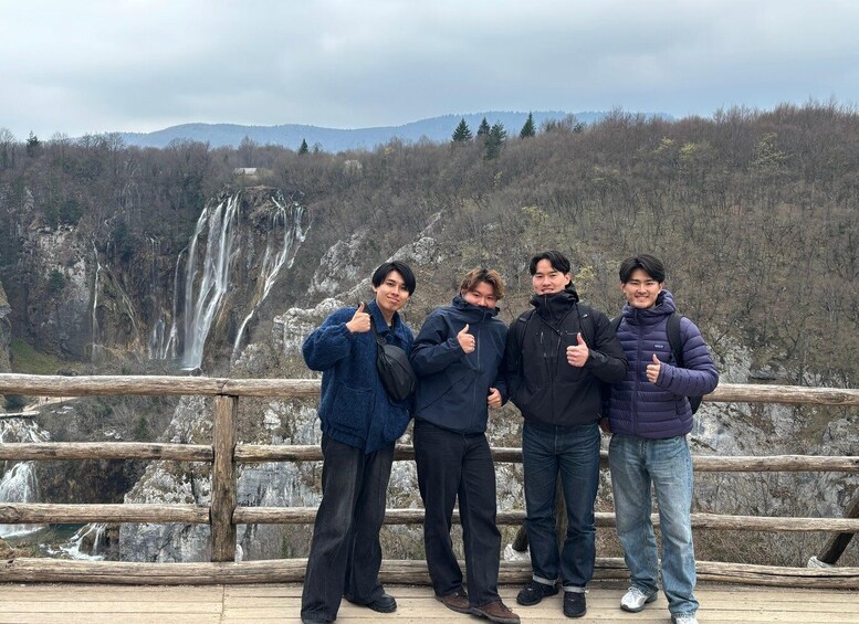 A group of people standing on a wooden platform with a waterfall in the background. 5