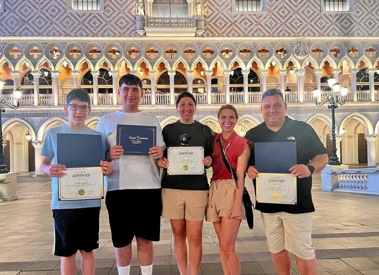 A group of people holding certificates in a building with ornate arches and columns. 2