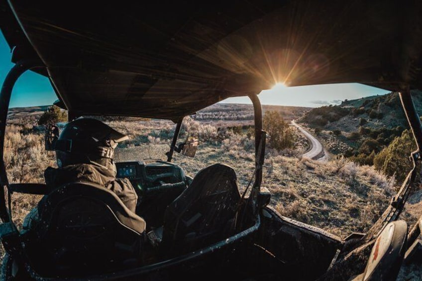 A person in a vehicle with a sun setting in the background. 4