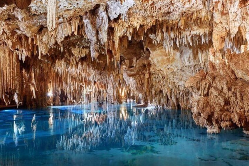 En grotta med stalaktiter och stalagmiter, en liten sjö och en båt. 4