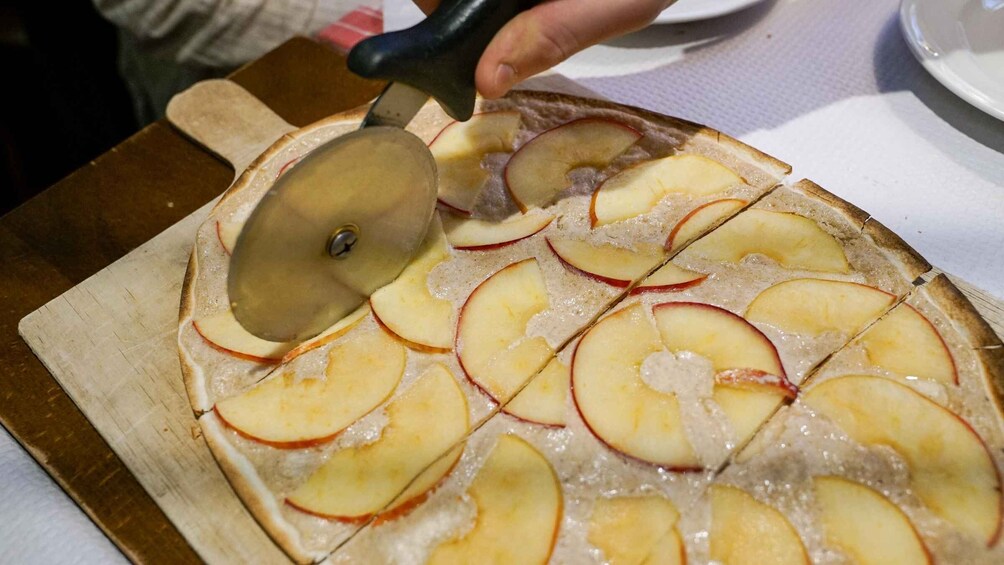 A person slicing a pie with apple slices on top. 3