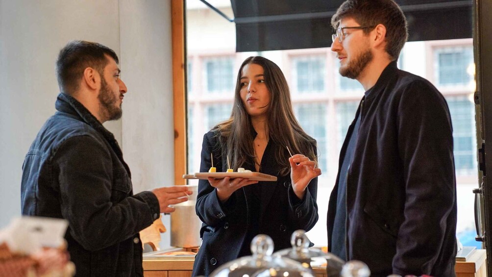 Three people in a cafe, one holding a plate with food items. 2
