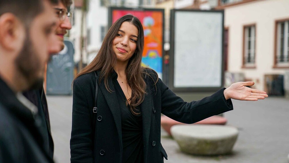 A person in a black coat gesturing with their hand. 5