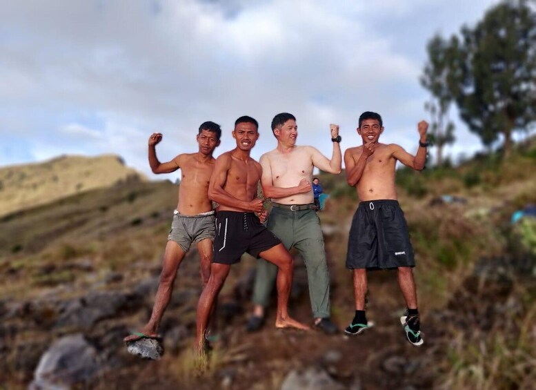 Four men standing on rocky terrain with a hilly landscape in the background. 5