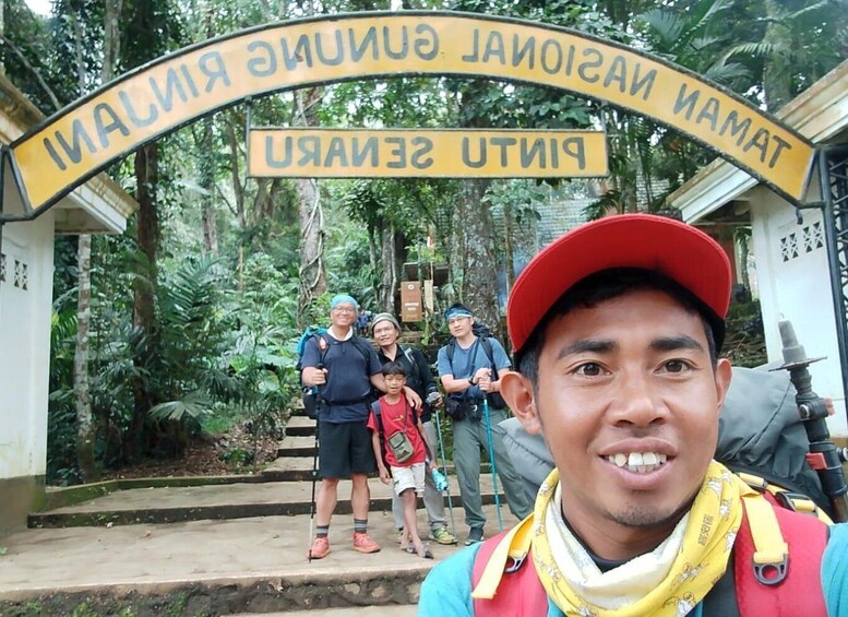 A group of people at the entrance of a national park, with a sign indicating the name of the park. 3