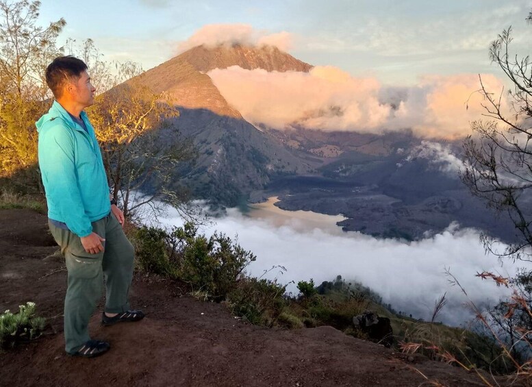 A person standing on a hillside overlooking a valley with a mountain in the background. 4