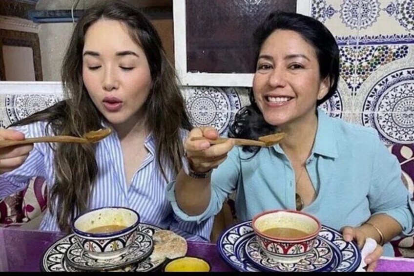 Two people sitting at a table with bowls of food and chopsticks. 3