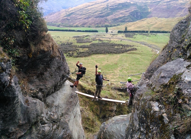 A group of people on a suspension bridge in a mountainous area. 4