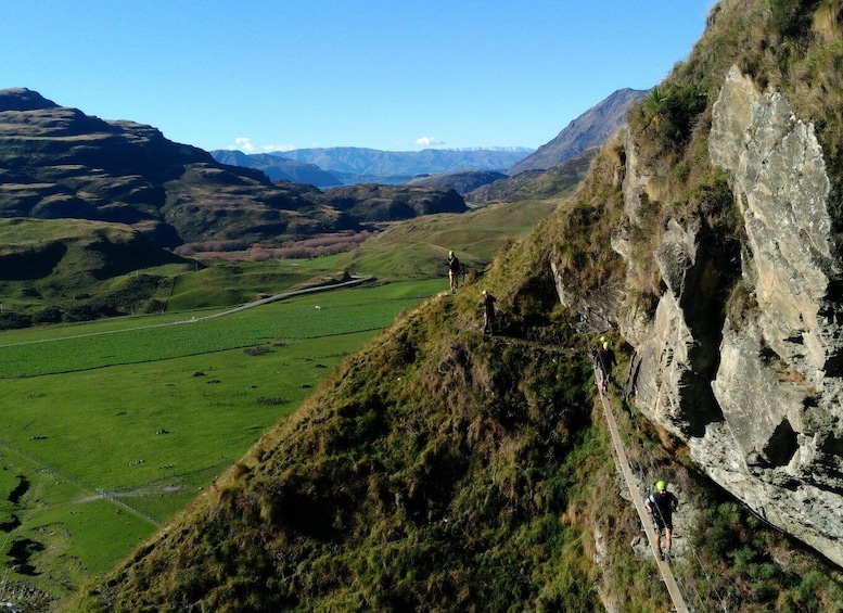 A mountainous landscape with a narrow path, green fields, and distant mountains. 2