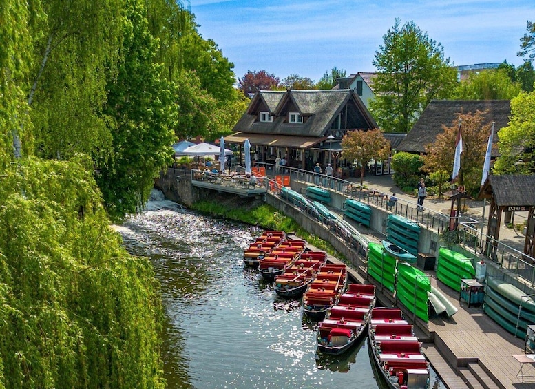 A riverside with boats docked, a wooden building, and lush greenery. 1