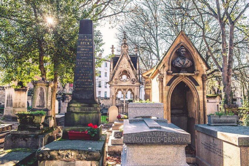 A cemetery with gravestones, a monument, and a gothic chapel. 4