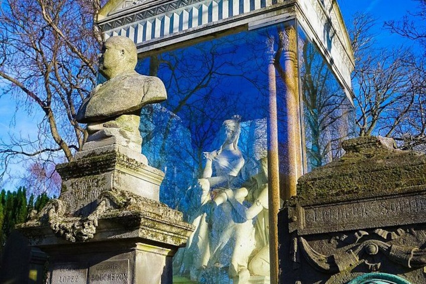 A stone statue with inscriptions, a glass window, and a tree in the background. 2
