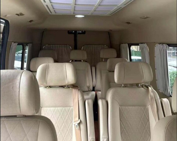 A vehicle interior with beige seats, a central aisle, and a ceiling light. 3