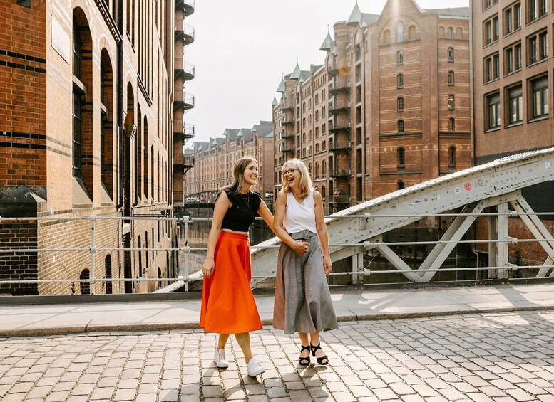 Two people standing on a bridge with historic buildings in the background. 3