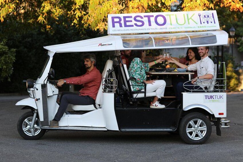 Een witte tuk-tuk met een bord waarop staat 'RESTOTUK' en 'LES MEILLEURS RESTAURANTS EN TOUTE LIBERTÉ'. 2
