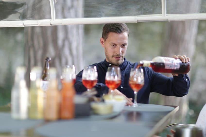 Iemand giet een rode vloeistof in een glas. 3