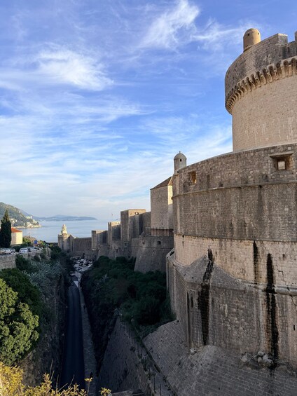 A historic stone fortress with a moat, overlooking a coastal city. 5