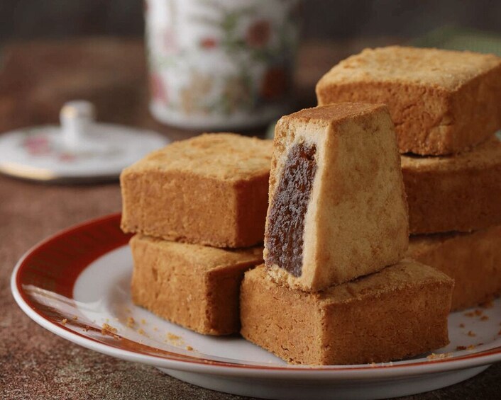 A stack of square-shaped sponge cakes with a jam filling on a plate. 2