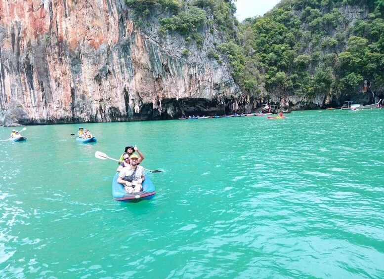A group kayaking on turquoise water with rocky cliffs in the background. 4
