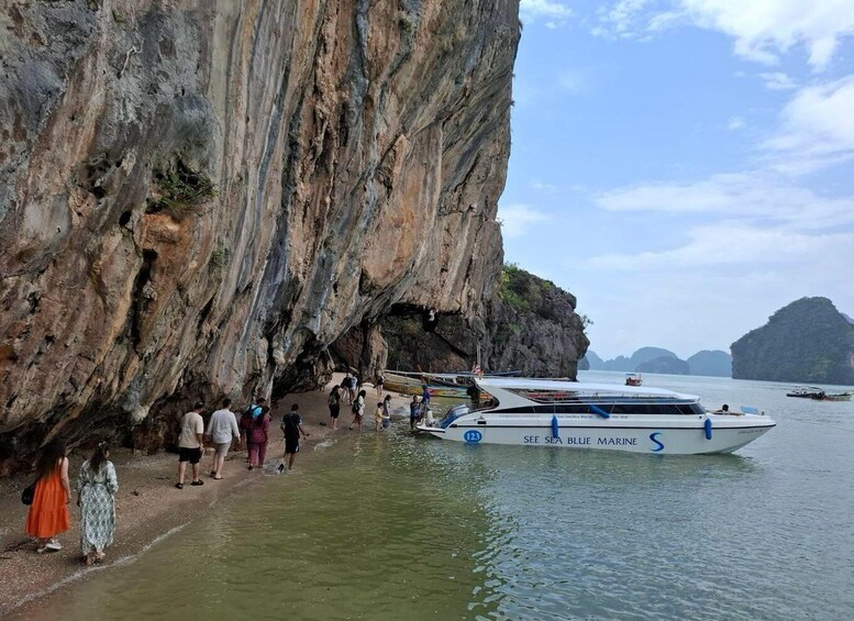 A rocky cliff with a boat named 'SEE SEA BLUE MARINE' docked at its base, surrounded by calm water and distant islands. 2