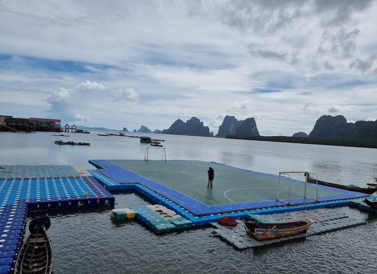 A calm body of water with a floating platform, boats, and distant mountains. 5