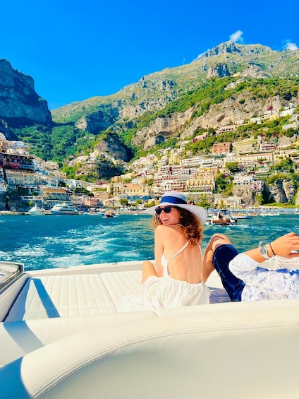 A person on a boat with a mountainous coastal town in the background. 3