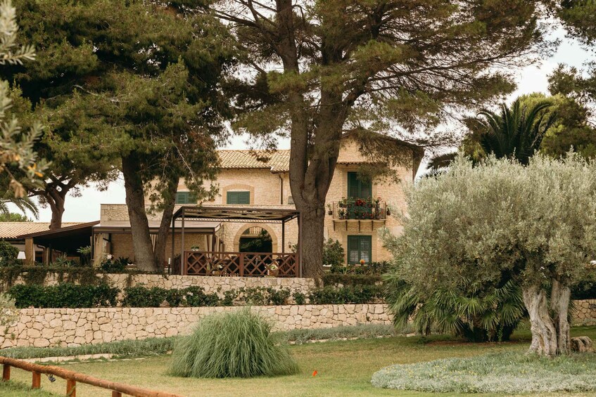 Un bâtiment en pierre, doté d’un toit en tuiles, entouré d’arbres et d’un jardin bien entretenu. 2