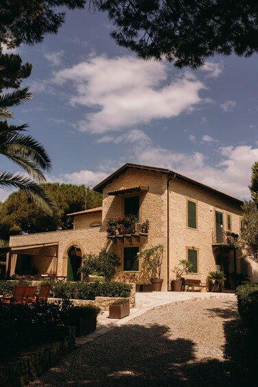 Une maison en pierre avec un toit en tuiles, entourée de verdure et dotée d’une allée gravillonnée. 3
