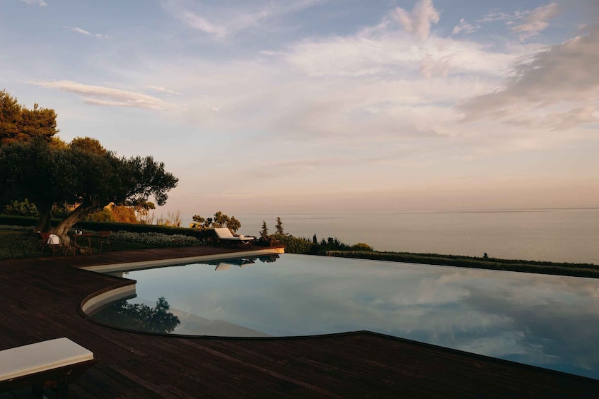 Une piscine paisible, dotée d’une terrasse en bois, entourée d’une végétation luxuriante et offrant une vue sur une mer calme. 4