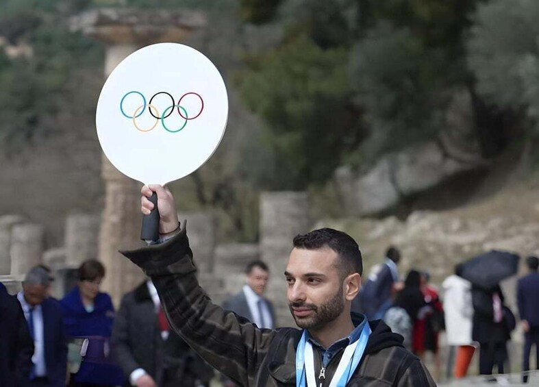 A person holding a white sign with the Olympic rings. 1