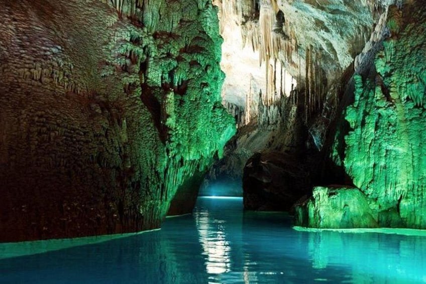 A cave with stalactites and stalagmites, illuminated by green lighting, and a pool of water at the bottom. 3