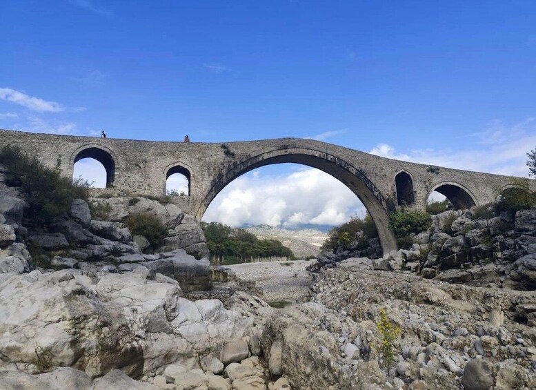 An ancient stone bridge with multiple arches over a rocky terrain. 4