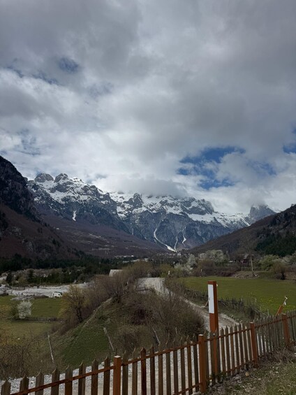 A mountainous landscape with snow-capped peaks, a wooden fence, and a clear sky. 2