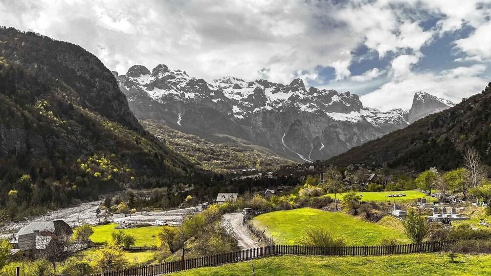 A mountainous landscape with a river, green fields, and a cemetery. 1