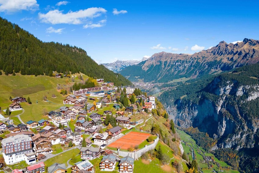 A mountainous village with traditional houses, a valley, and snow-capped peaks. 2
