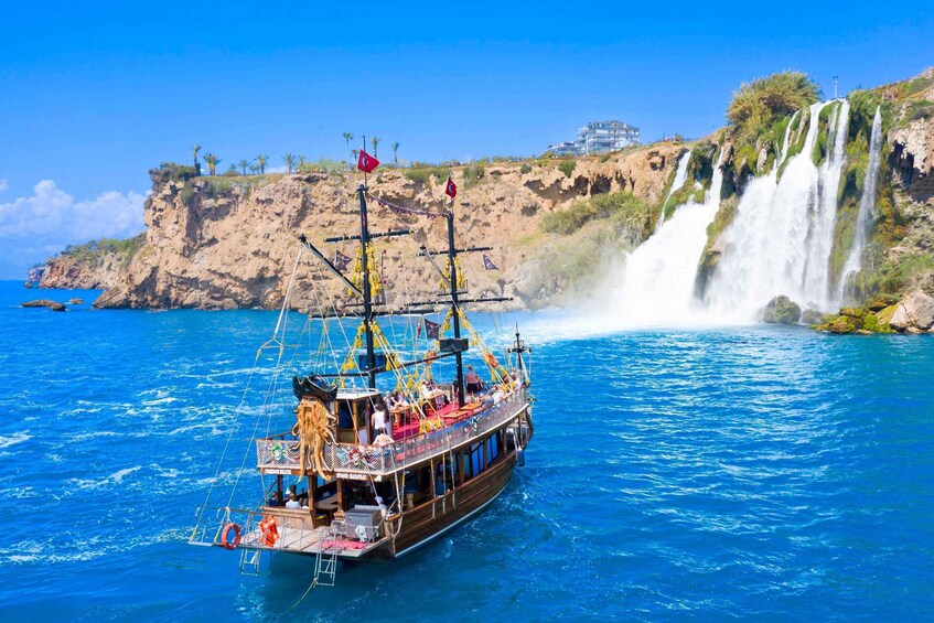 A boat with passengers, a coastal cliff, and a waterfall. 1