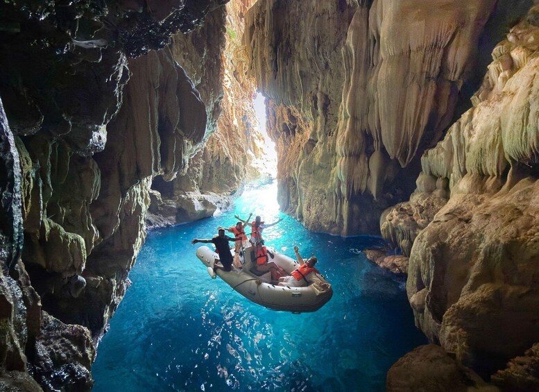 A group of people rafting in a narrow, rocky canyon with clear blue water. 4