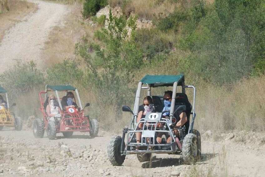Off-road vehicles on a dirt path with vegetation on the sides. 2