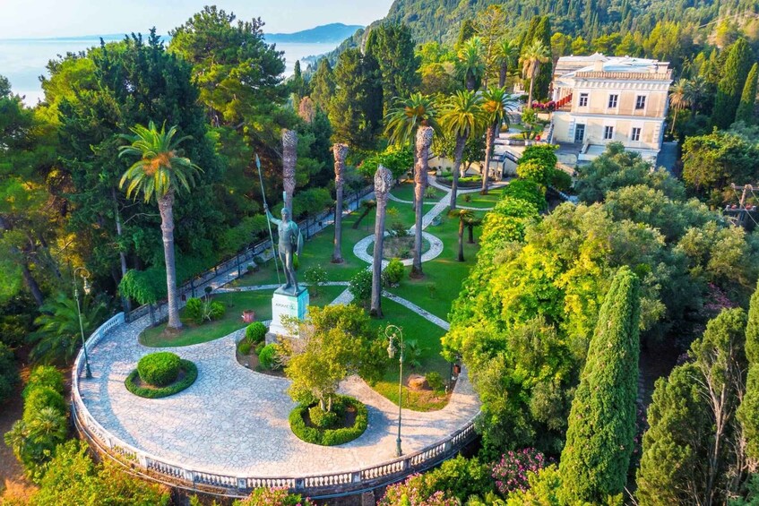 A landscaped garden with a statue, palm trees, and a building. 3