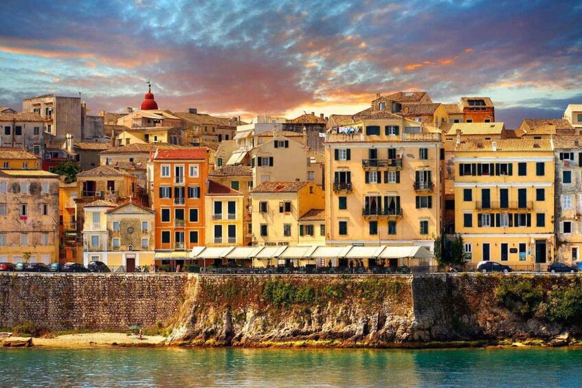 A coastal cityscape with historic buildings, a prominent red dome, and a stone wall along the waterfront. 2