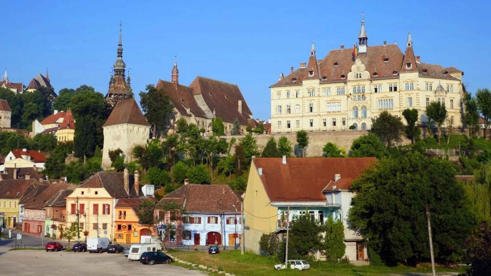 A historic town with colorful buildings, a prominent church tower, and a large castle-like structure. 3