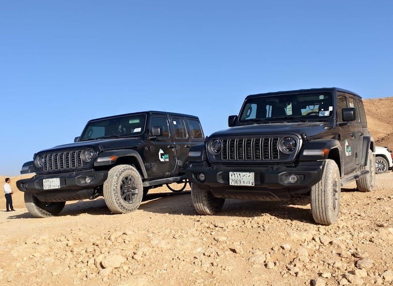 Two black off-road vehicles parked on a rocky terrain with a clear sky. 3