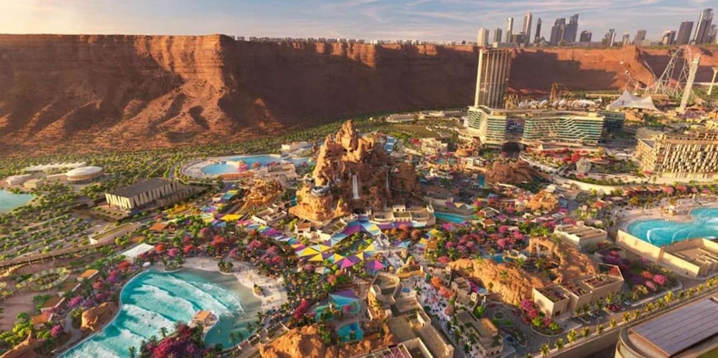 A resort with multiple pools, a large rock formation, and a city skyline in the background. 3