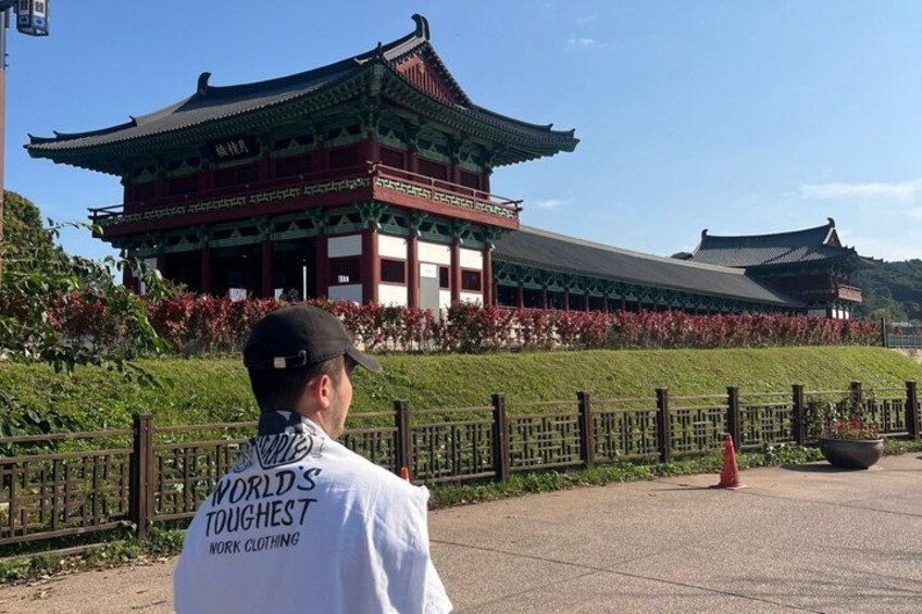 A traditional Korean building with a red roof and green eaves, surrounded by a well-maintained garden with red flowers. 3