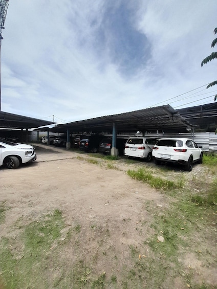 A parking area with several cars, a covered structure, and a dirt path. 5